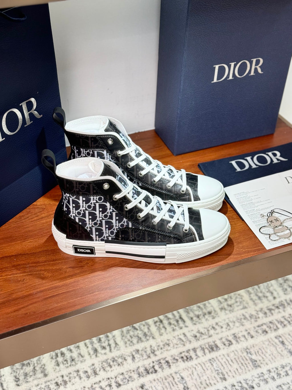Black-and-white monogram high-top sneakers with white laces and flat rubber sole