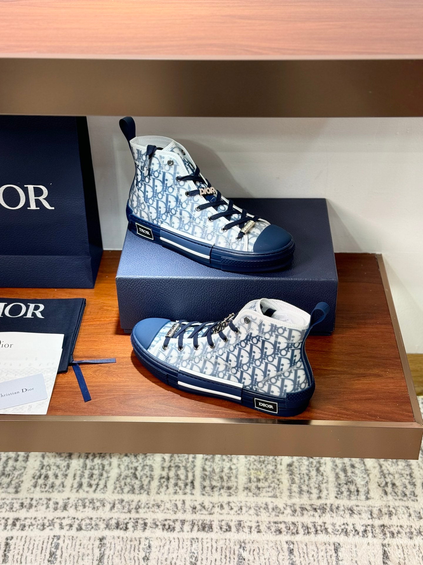 Two high-top sneakers with Dior monogram fabric and blue laces in box