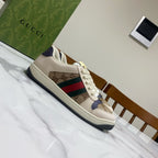 Gucci unisex sneakers, side view, beige upper with logo print and color stripe.
