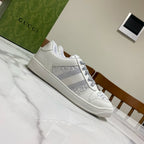White Gucci unisex low-top sneakers with gray striped panel and lace-up closure
