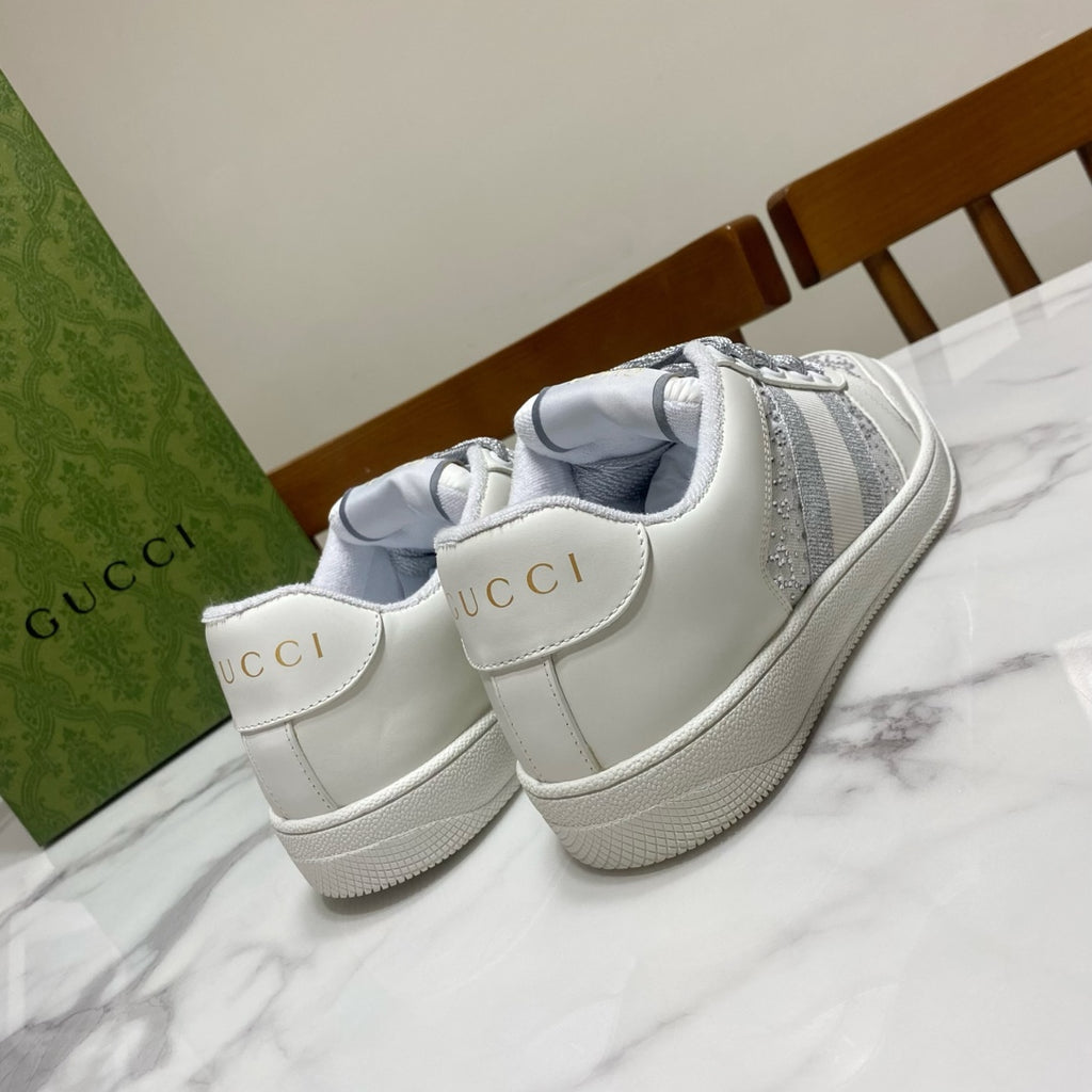 White Gucci unisex sneakers with “GUCCI” heel tabs and gray side stripes