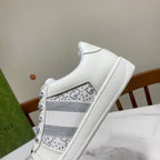 White Gucci unisex sneaker side view with gray striped panel and lace eyelets