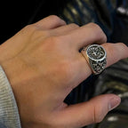 Chrome ring on hand, oval emblem with floral engravings and detailed band
