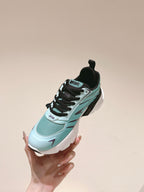 Mint and black sneaker held in hand, side profile with Dior branding and chunky sole
