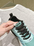 Close-up of mint lace-up sneaker with black laces and Dior logo detail on side