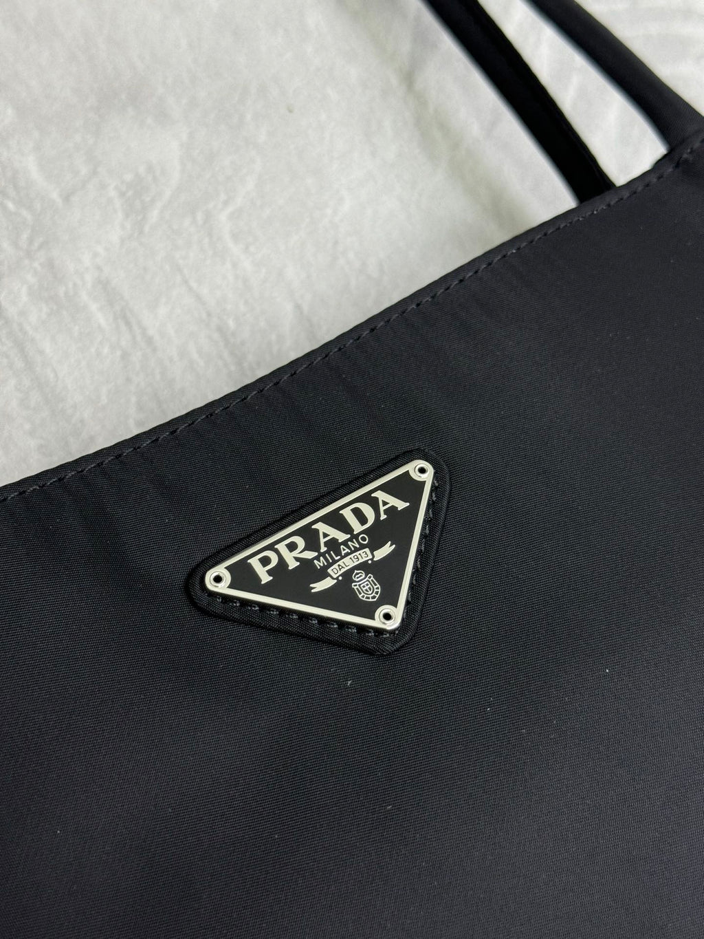 Black tote bag close-up of front logo plate