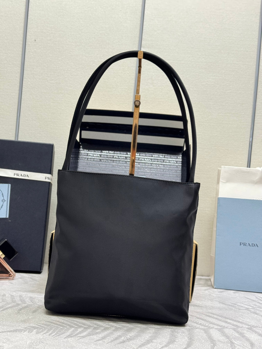 Black tote bag with top handles and front logo plaque