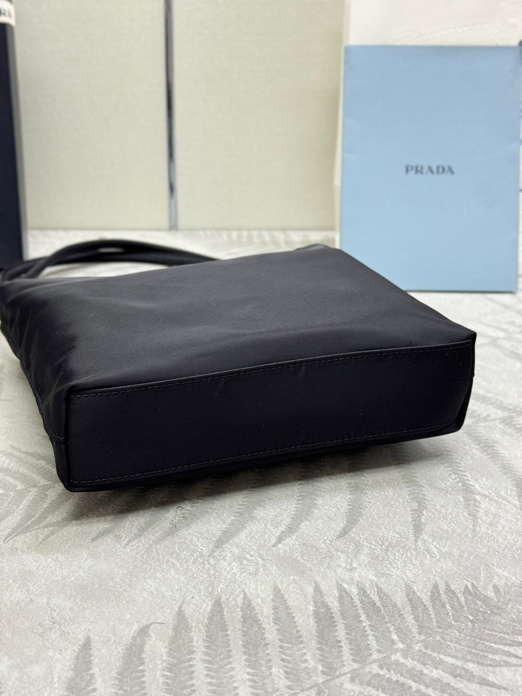 Black tote bag laid on side with structured base and top handles