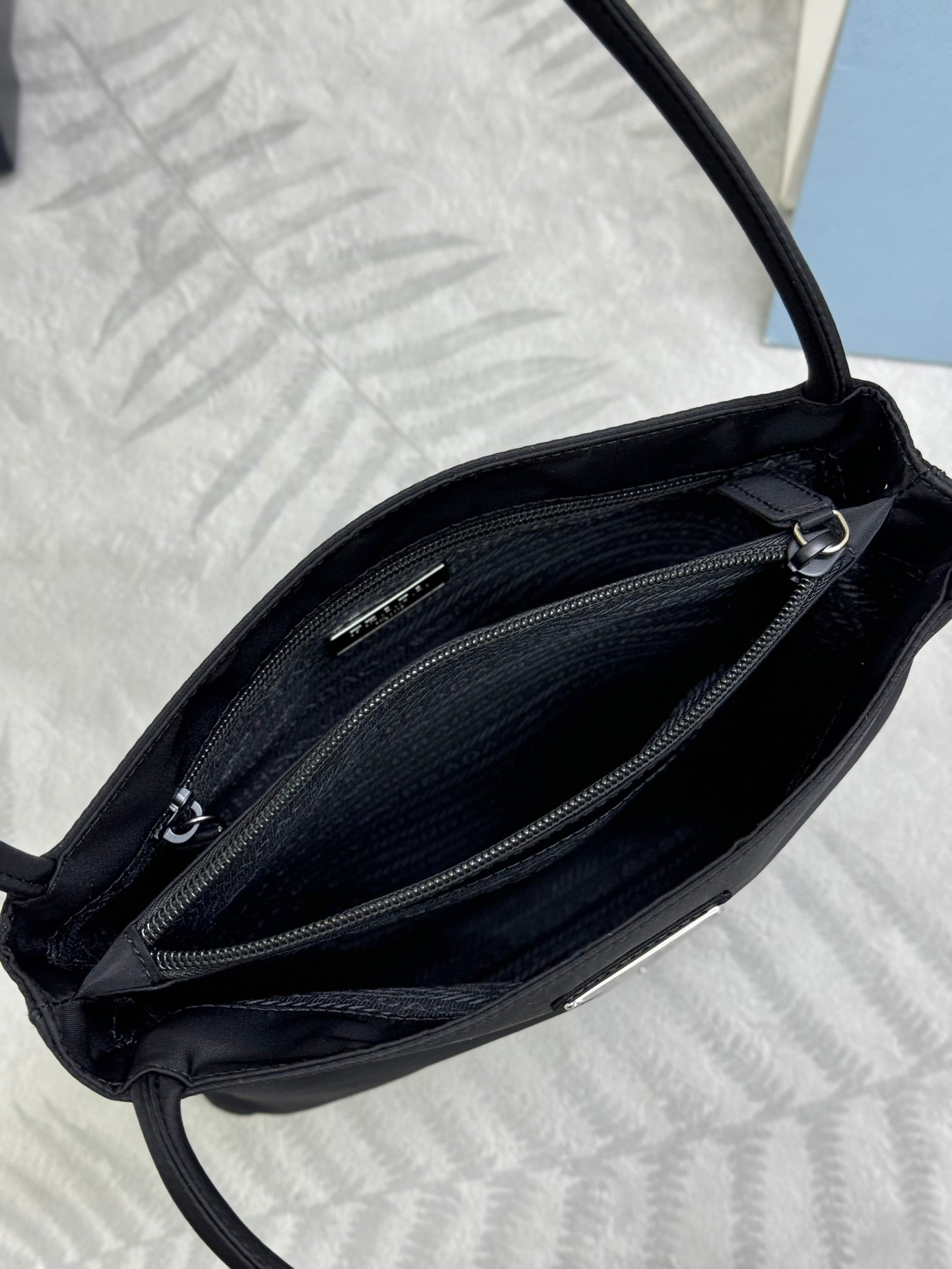 Black tote bag open view showing zipped inner compartments