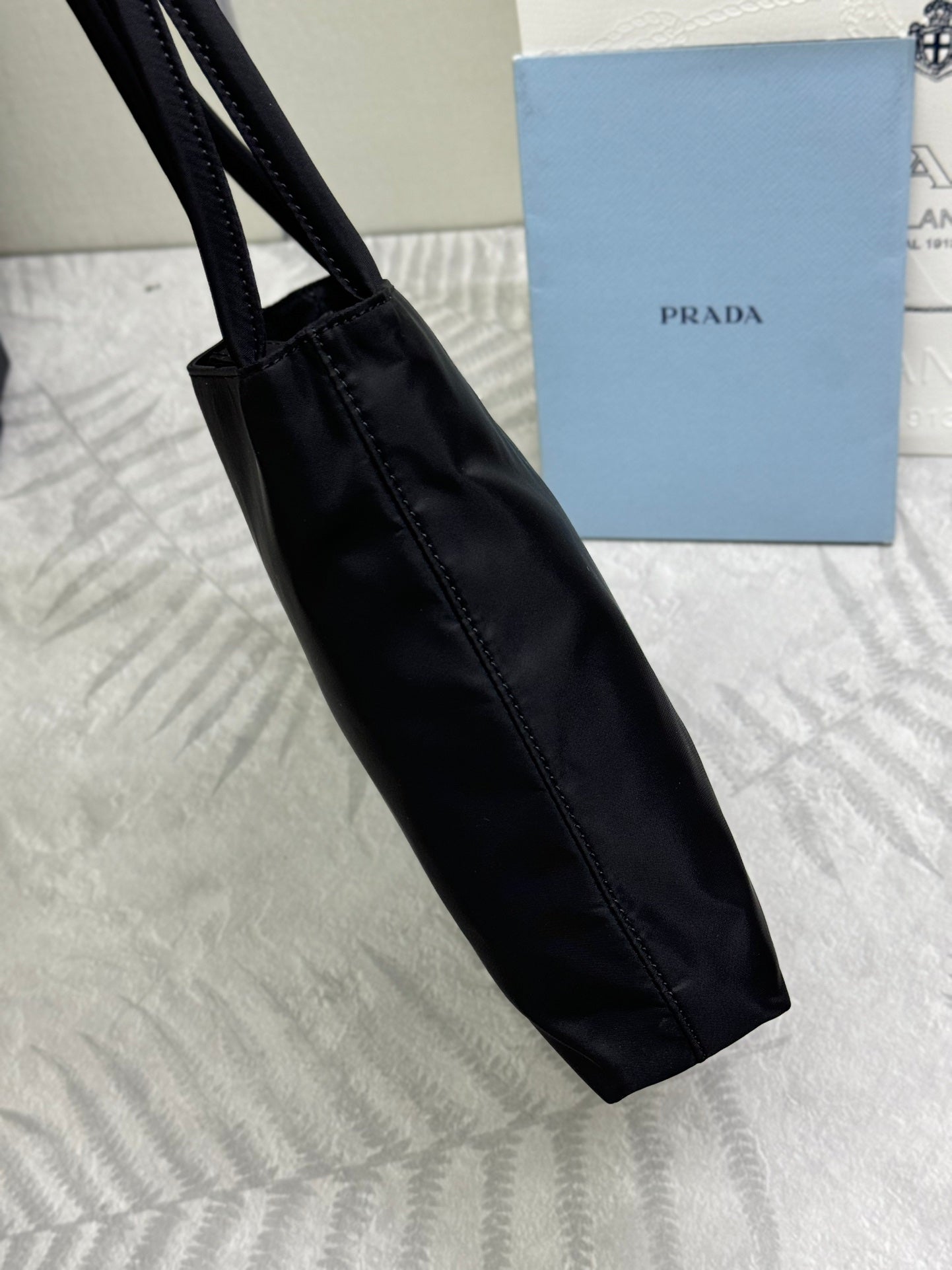 Black tote bag side view with long handle and stitched trim