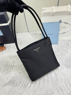 Black tote bag angled view with top handles and front logo plaque