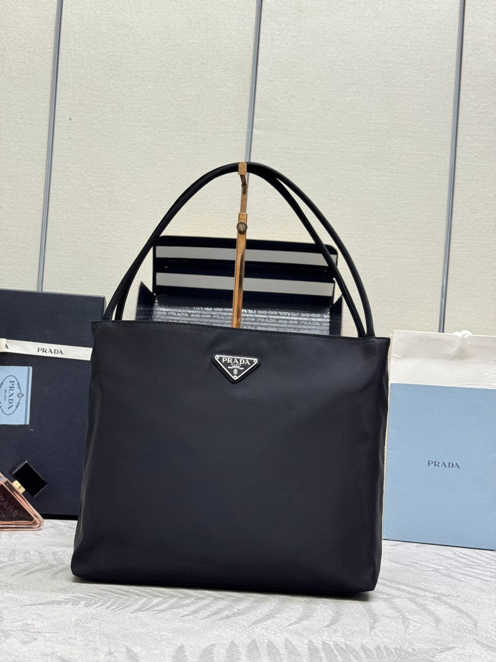 Black Prada tote bag with dual top handles and front triangular logo plate.