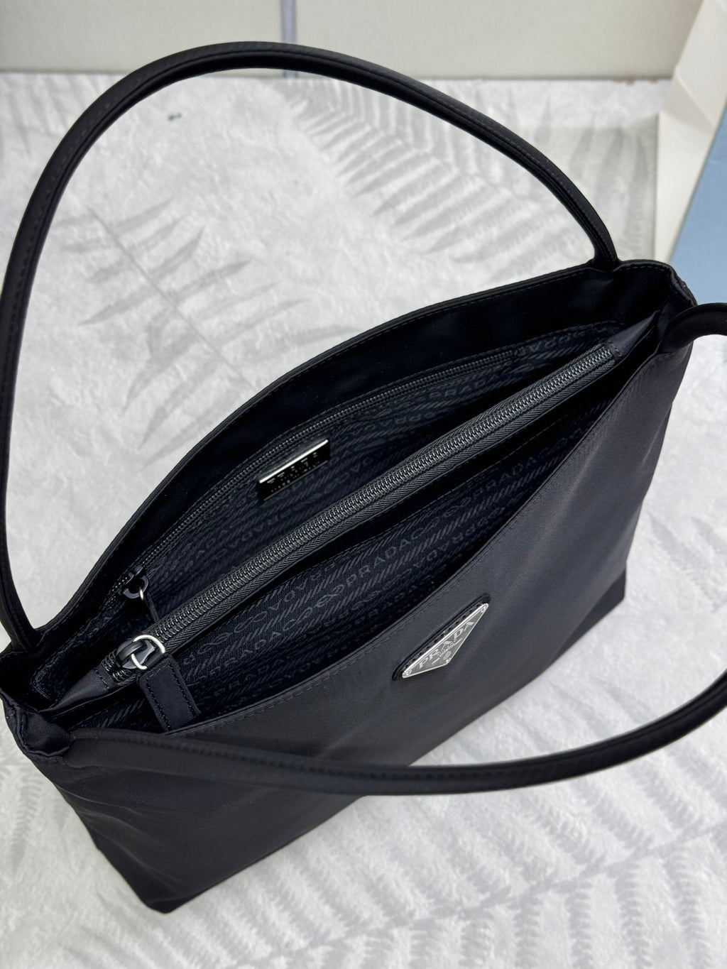 Black Prada tote bag interior view with two zip pockets and slip compartments.
