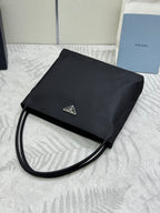 Black Prada small tote bag with long strap and foldover flap with logo plate.