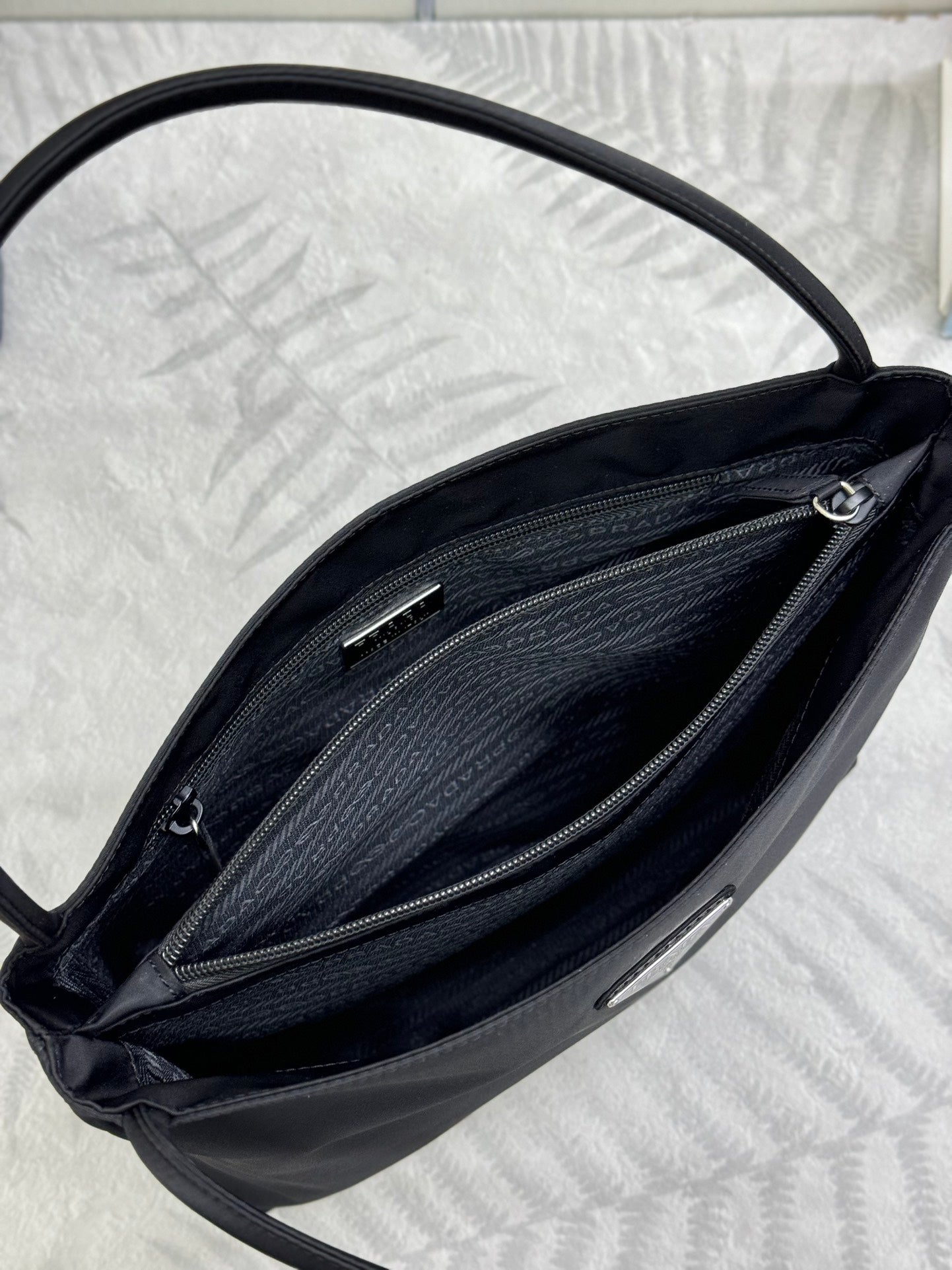 Black Prada tote bag interior close-up showing twin zip compartments and hardware.