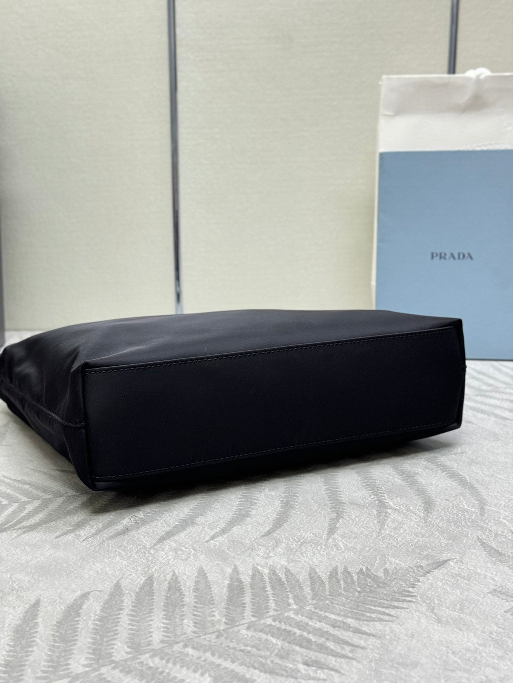 Black Prada tote bag with structured shape and wide bottom view.
