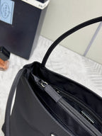 Black Prada tote bag top opening close-up with zip track and metal pull tabs.