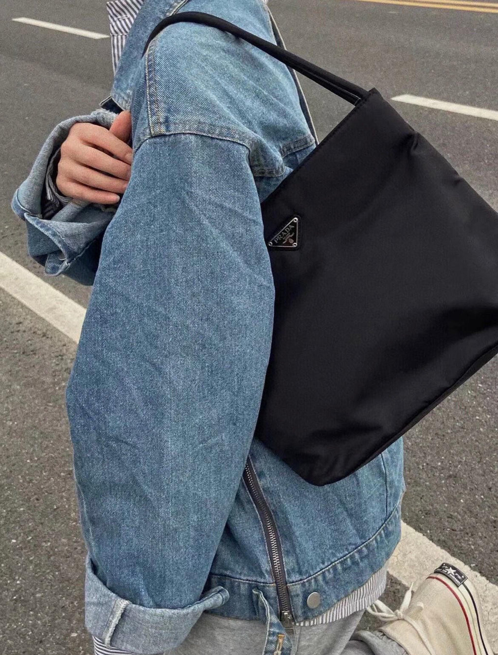 Prada black tote bag, side angle, top handles and triangular logo plaque