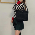 Prada black tote bag with top handles and triangular logo plaque, held up