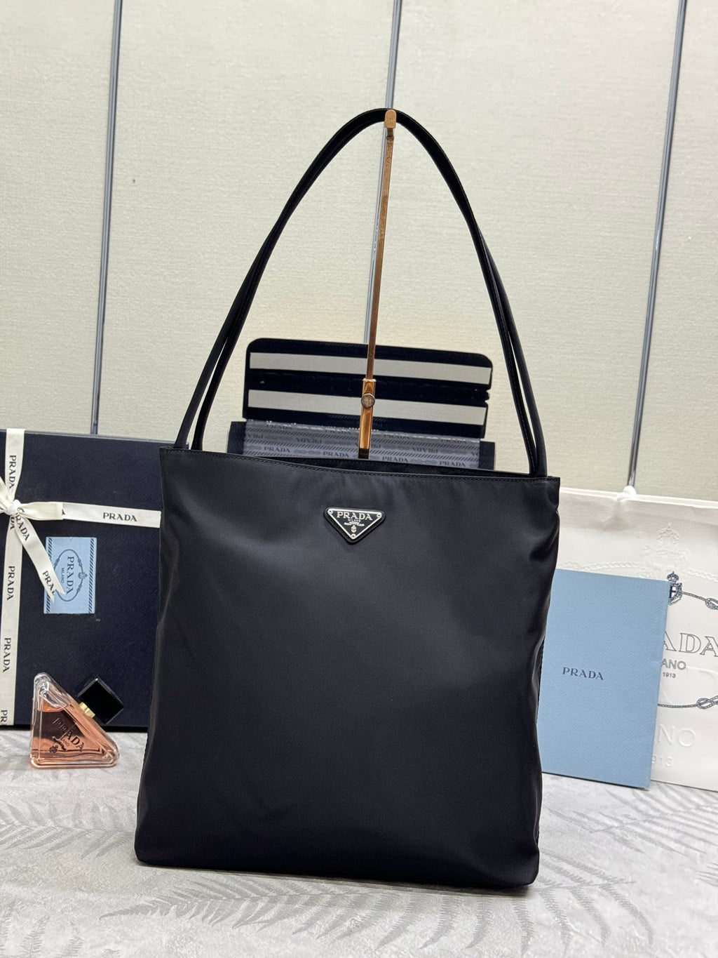 Prada tote bag in dark nylon with top handles, gold rings, and striped front detail