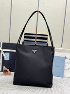 Prada tote bag in dark nylon with top handles, gold rings, and striped front detail