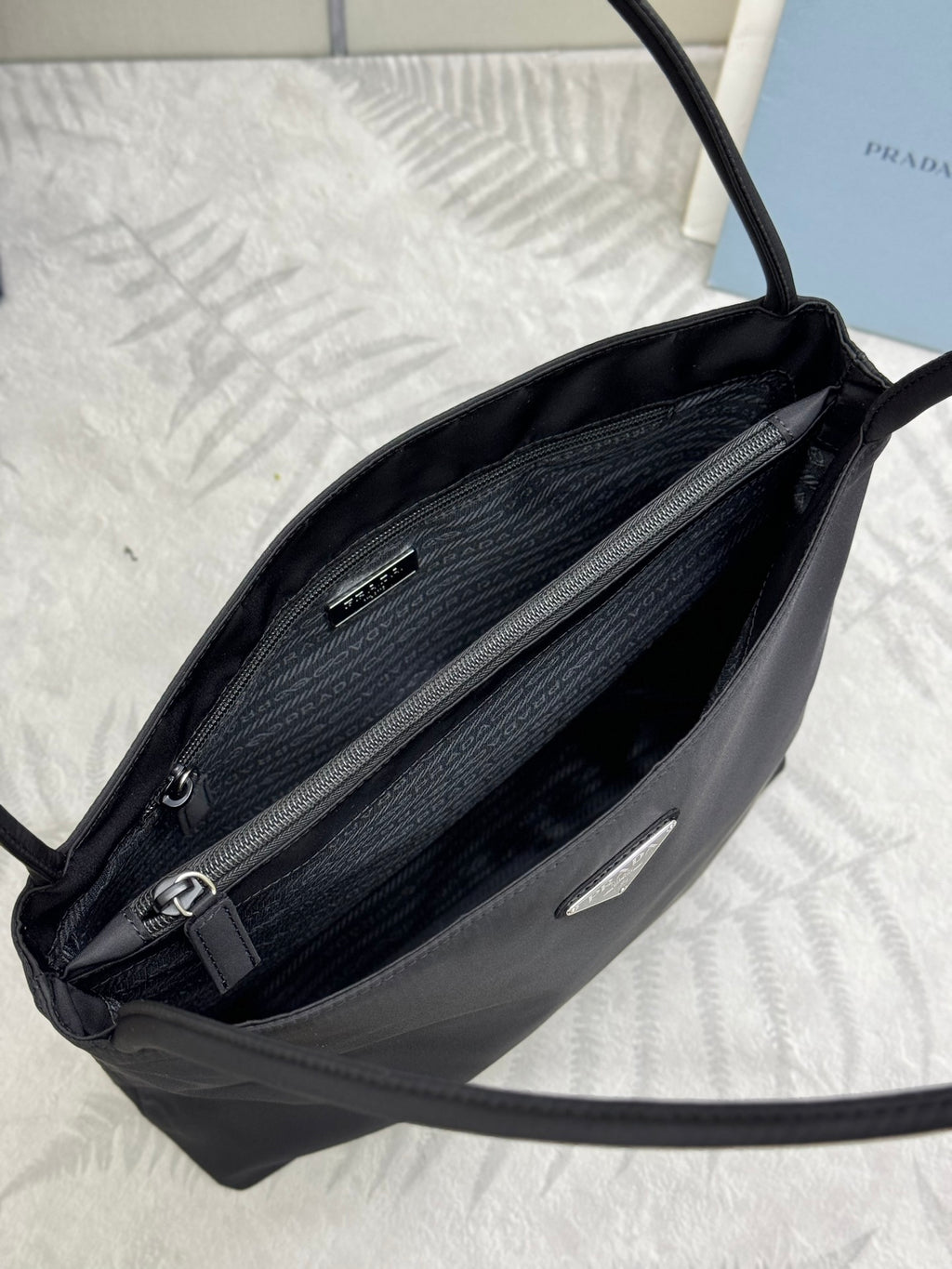 Prada mini tote bag interior view with dual compartments, zipper closure, and dark lining