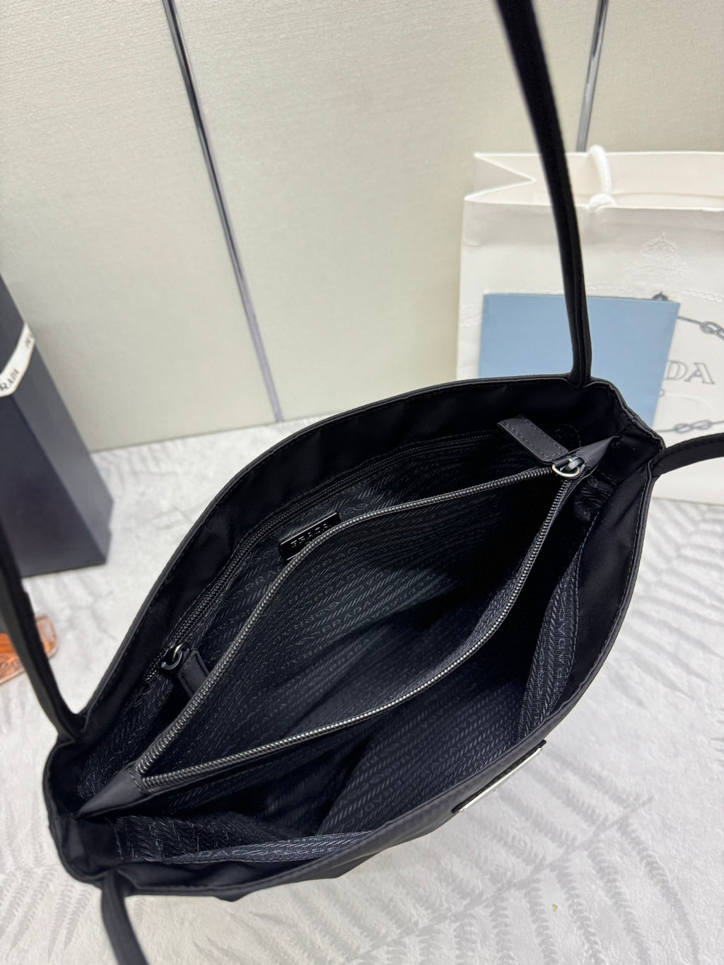Prada tote bag open view with dark lining, two zip pockets, and top zipper hardware
