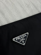 Prada logo patch on dark nylon fabric with metal triangle badge reading PRADA MILANO