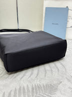 Prada tote bag in dark nylon, side view with structured rectangular shape and short handles