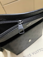 Louis Vuitton zipper pull and track on dark bag, close-up metal hardware