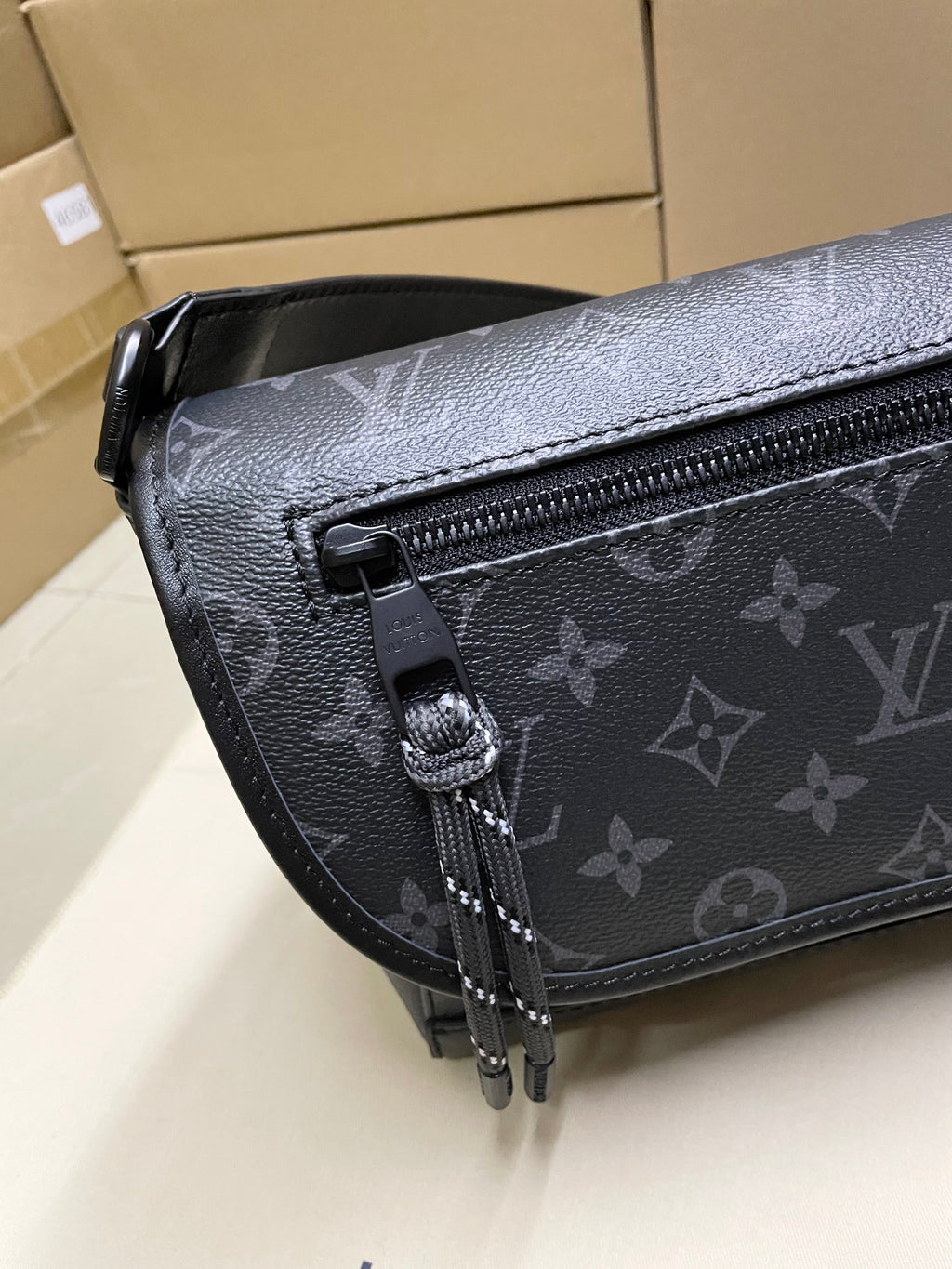 Louis Vuitton men's crossbody bag detail, dark monogram canvas and zipper pull