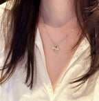 Silver-tone flower pendant necklace worn with a white V-neck blouse