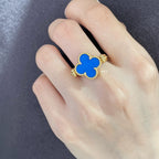 Clover-shaped ring on hand with blue enamel and gold filigree detailing