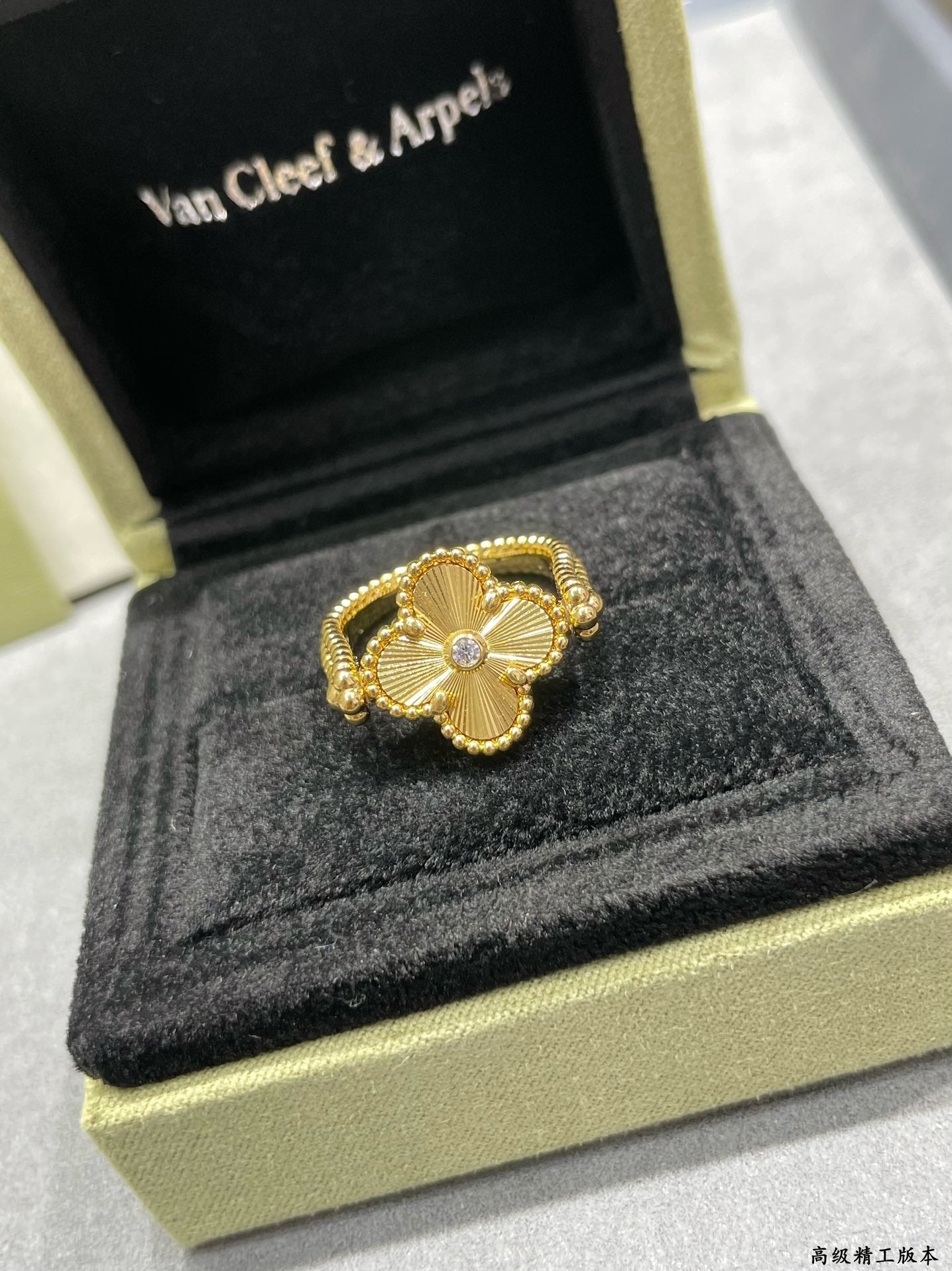 Gold clover-shaped ring with small clear center stone on a display box