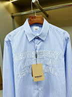 Light blue striped Burberry button-up shirt with large front logo print and tag