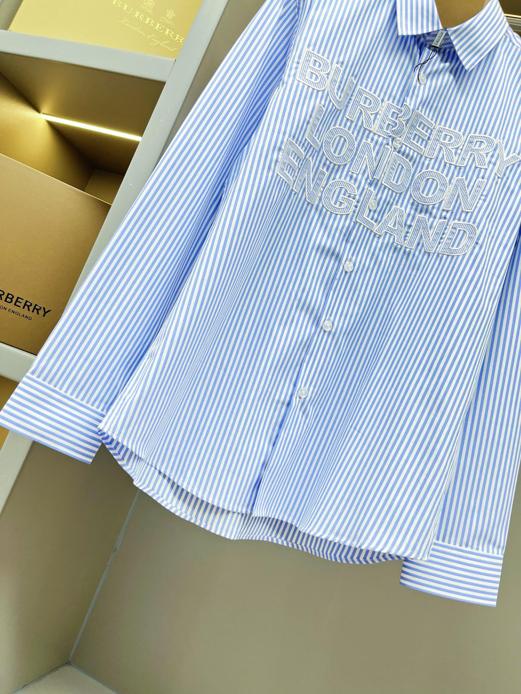 Light blue striped Burberry button-up shirt with rear logo print