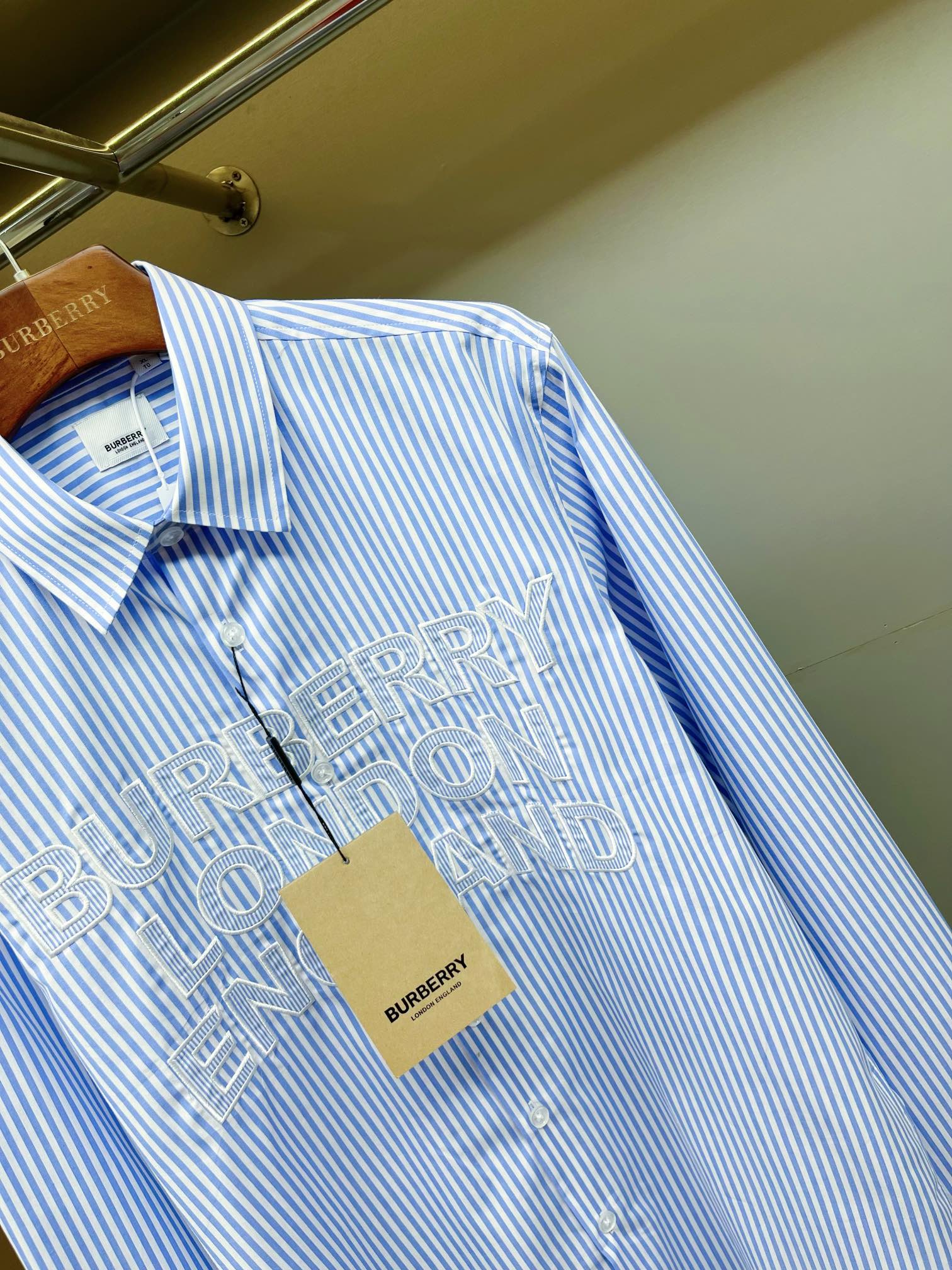 Light blue striped Burberry button-up shirt, front logo print close-up
