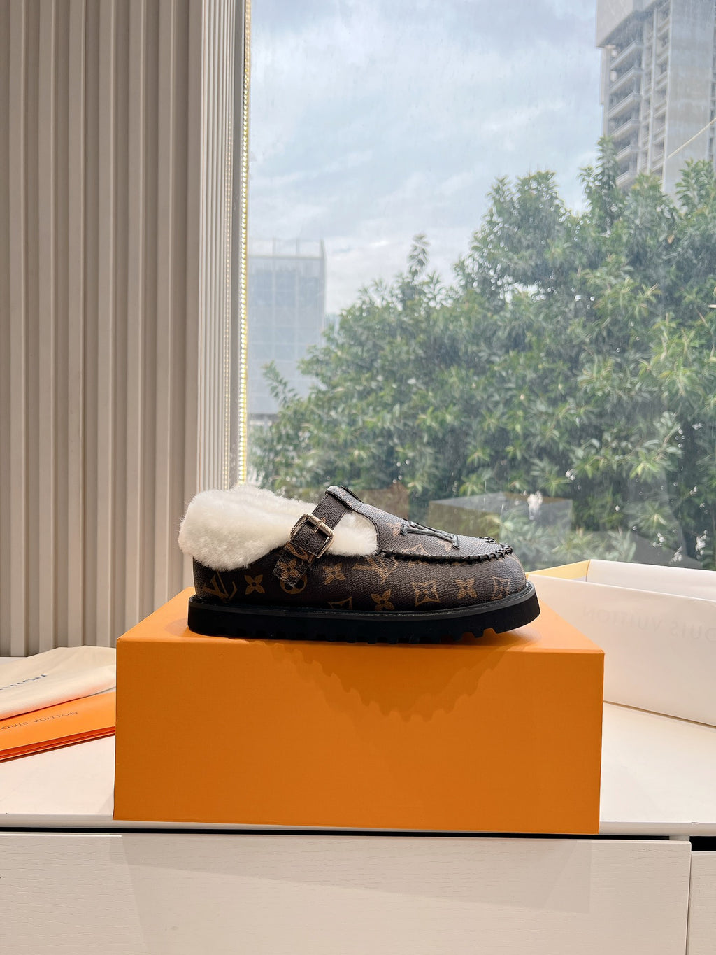 Louis Vuitton monogram loafer with white shearling lining and strap buckle, side view