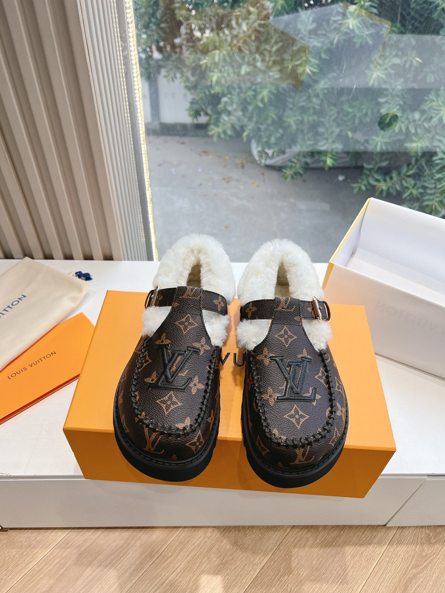 Pair of Louis Vuitton monogram loafers with white shearling lining and buckle straps