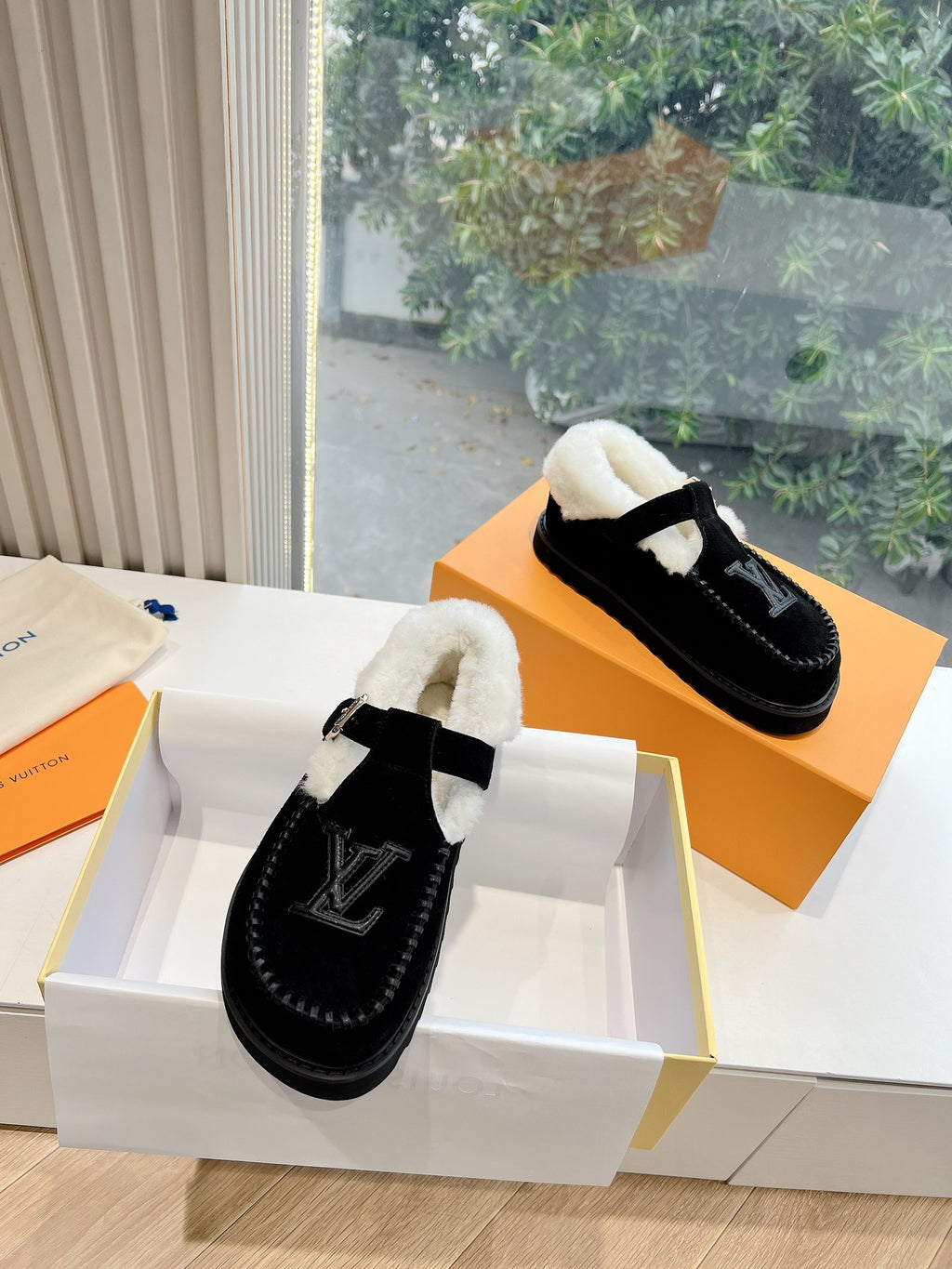 Black moc-style Louis Vuitton loafers with white shearling lining and LV emblem