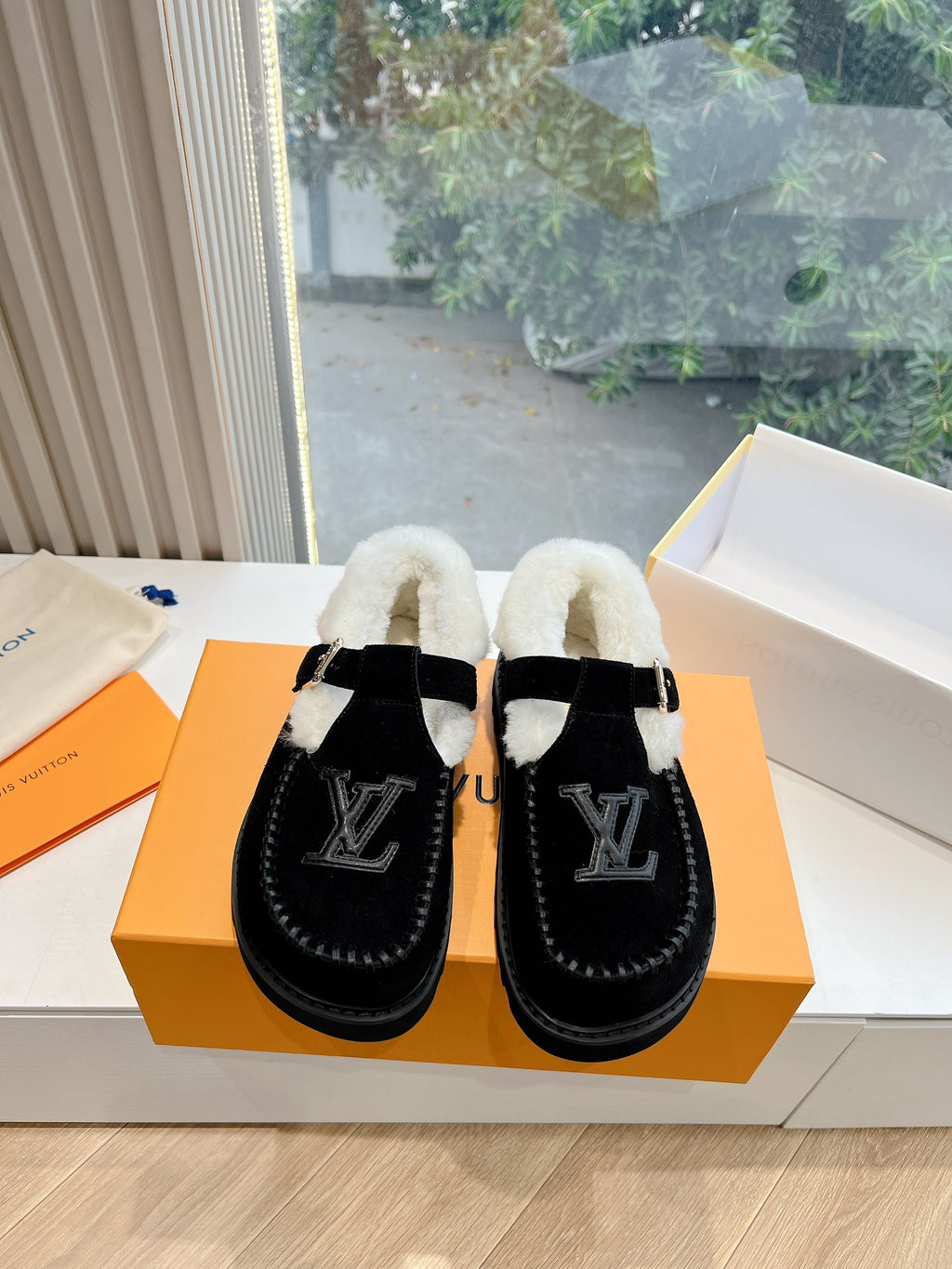 Pair of black Louis Vuitton unisex loafers with cream shearling lining and LV logo