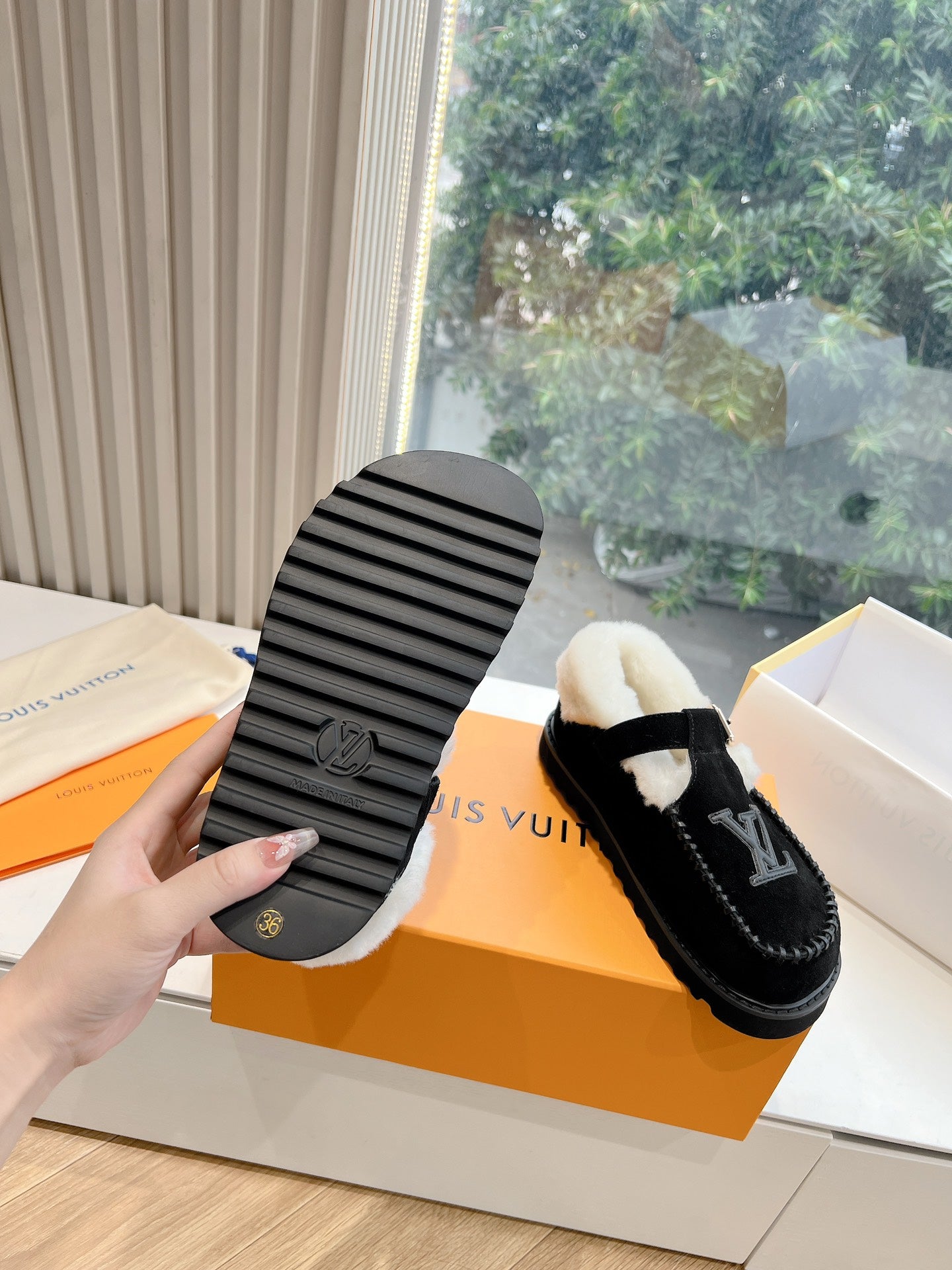 Bottom view of black Louis Vuitton loafers with striped tread and LV emblem