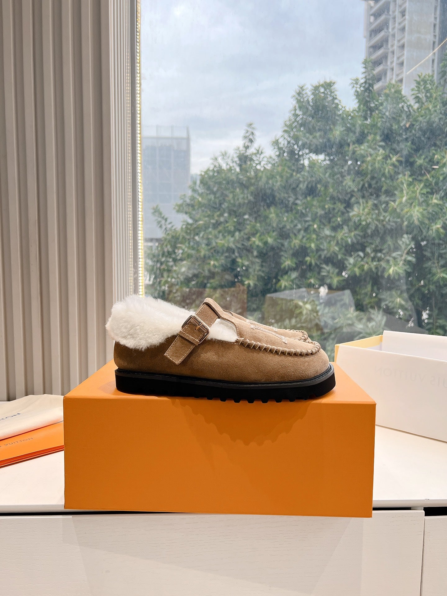 Louis Vuitton tan suede shearling mules with buckled strap and black sole edge