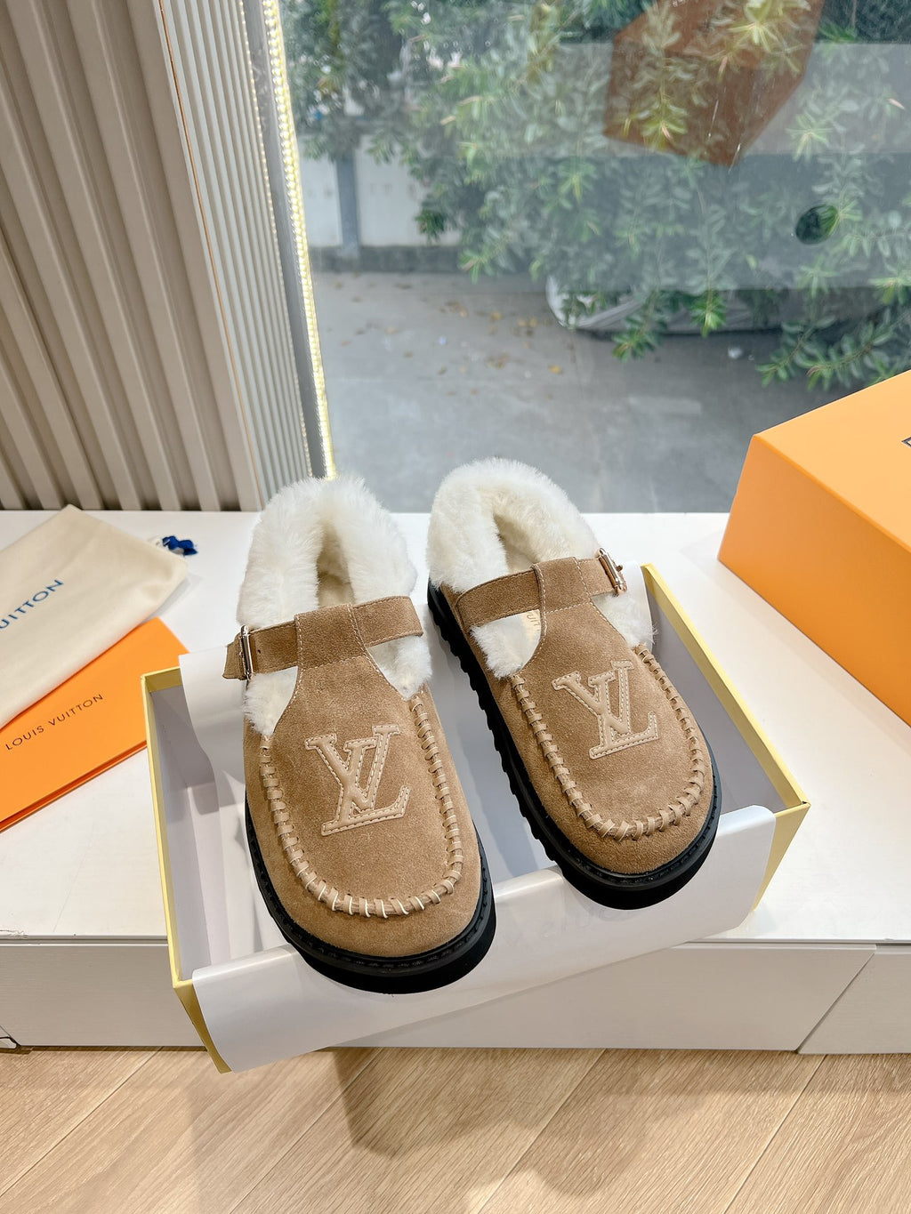 Louis Vuitton tan suede shearling mules with buckled strap and LV logo