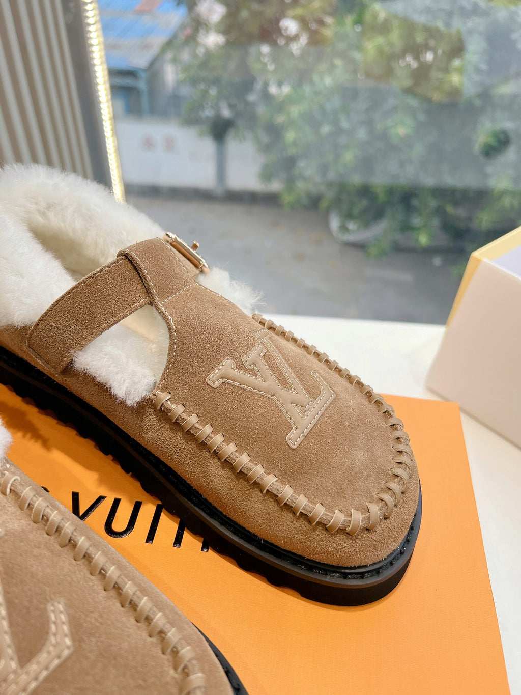 Louis Vuitton tan suede shearling mule with buckled strap and embossed LV logo