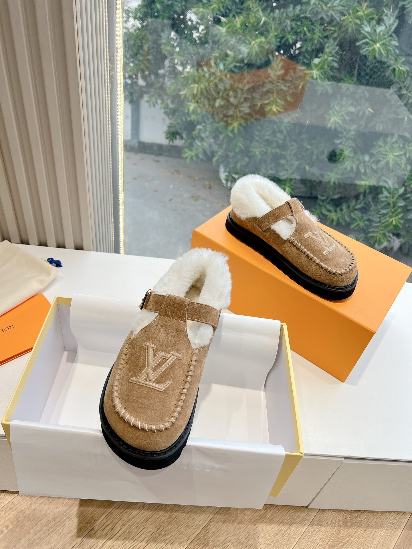 Louis Vuitton tan suede shearling mules with buckled strap and LV logo detail