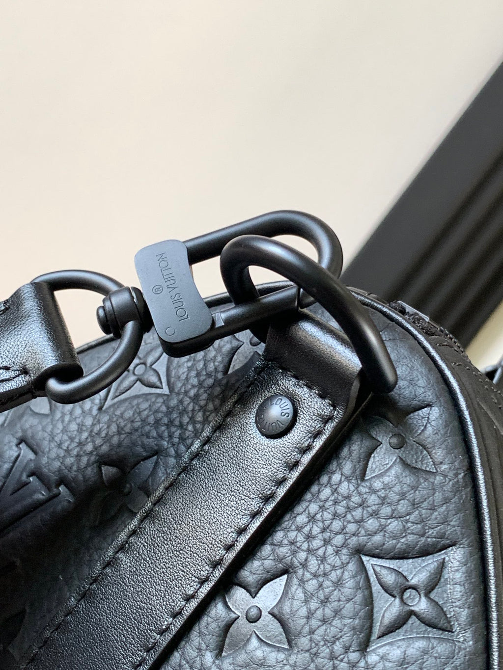 Dark monogram handbag corner with metal rings and textured leather detail