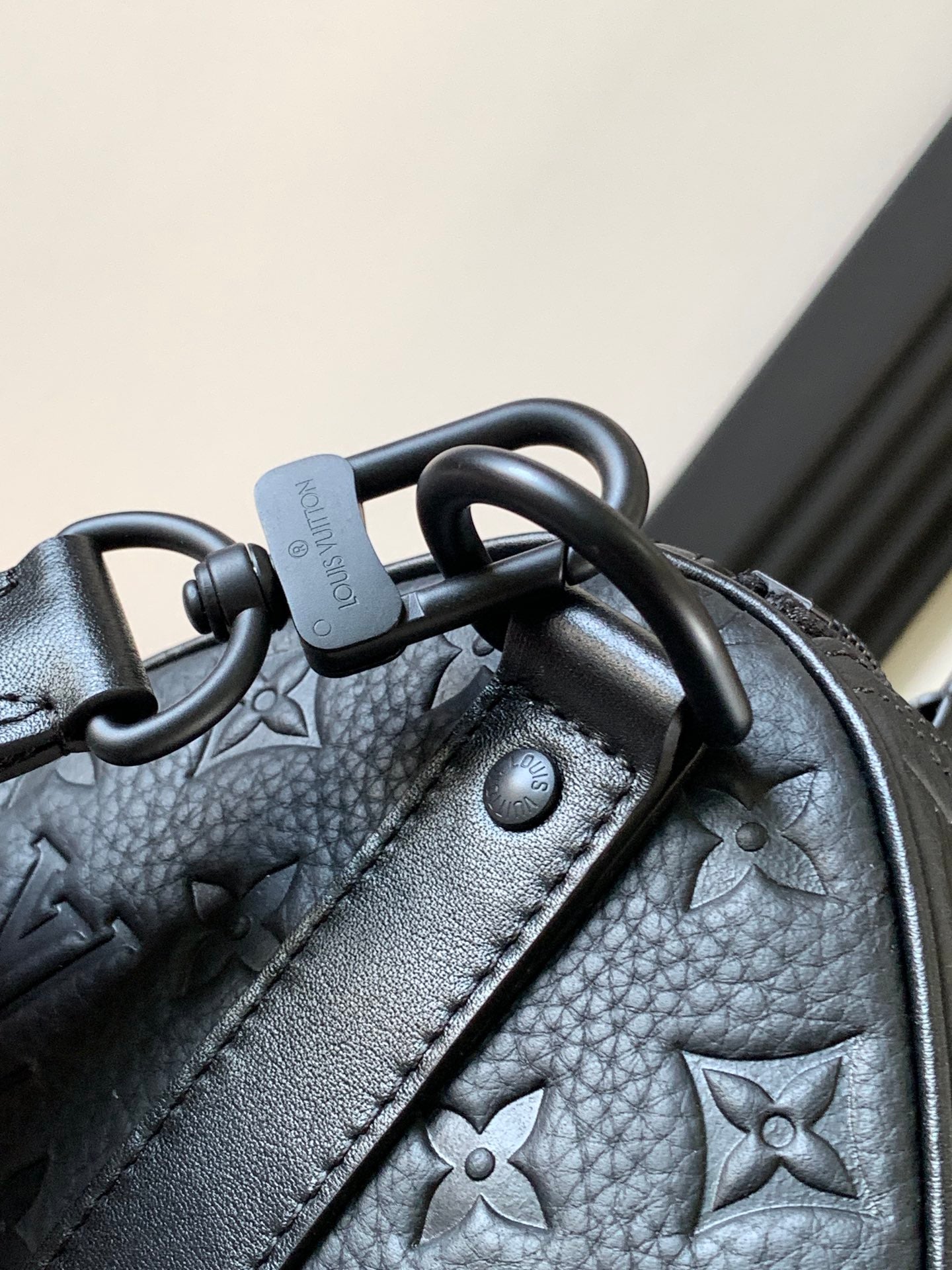 Dark monogram handbag corner with metal rings and textured leather detail