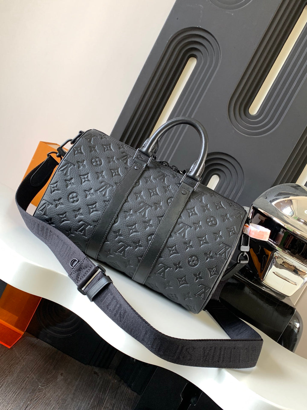 Dark monogram duffel bag with top handles and wide shoulder strap