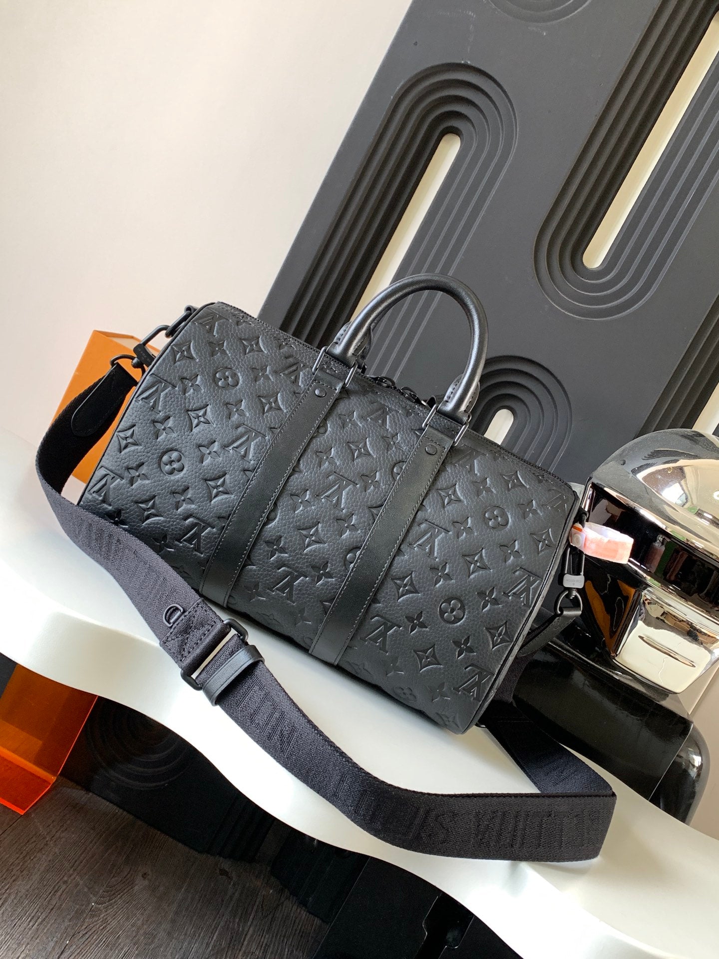Dark monogram duffel bag with top handles and wide shoulder strap